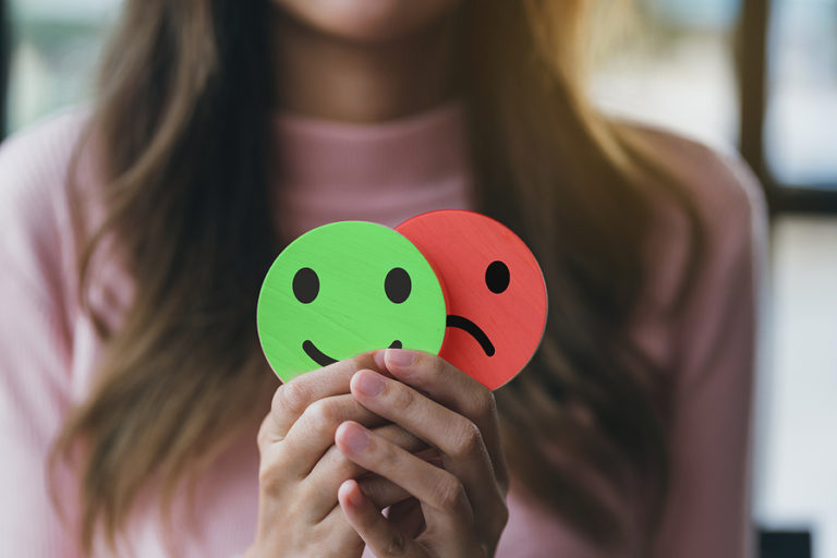 Psychology patient holding happy face and sad face stickers