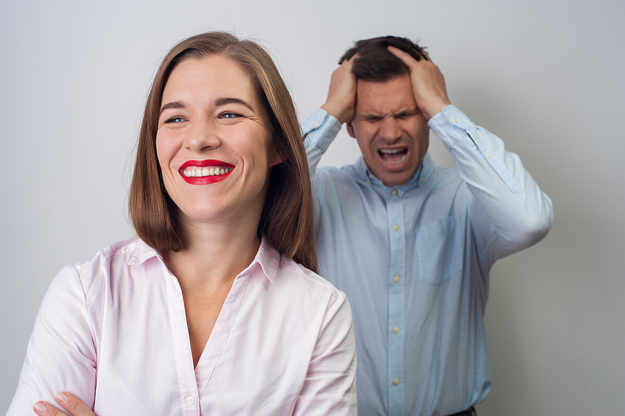 Narcissist woman smiling beside frustrated man.