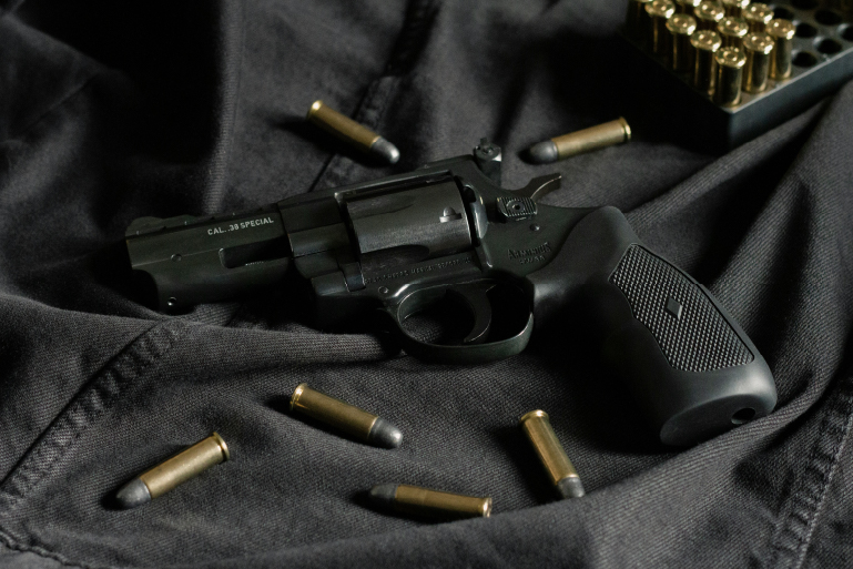 A photo of a gun and bullets on black canvas.