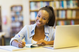 Psychology doctorate student with laptop studying in a library.