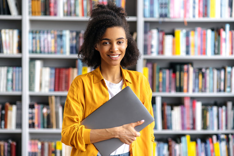 College student enrolled in a social work degree program at library with laptop