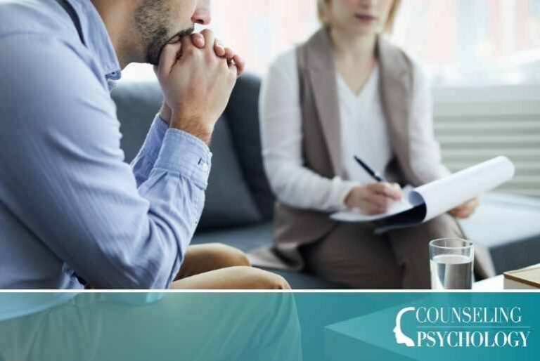 A mental health counselor sits with a patient in an office and takes notes.
